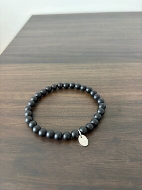 Tocara matte black bead stretch bracelet with a delicate silver oval charm tag.
